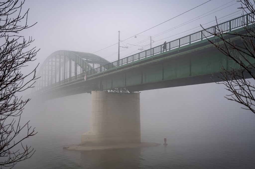 A pedestrian walks over a bridge in Belgrade, stretching over the Sava river, as heavy fog and air pollution dominate the sky over the Serbian capital Belgrade on January 15, 2020. - A thick cloud of pollution has been visible over the city for several days now, and according to the AirVisual app, Belgrade has several times in the last week been among the most polluted cities in the world. (Photo by Andrej ISAKOVIC / AFP)